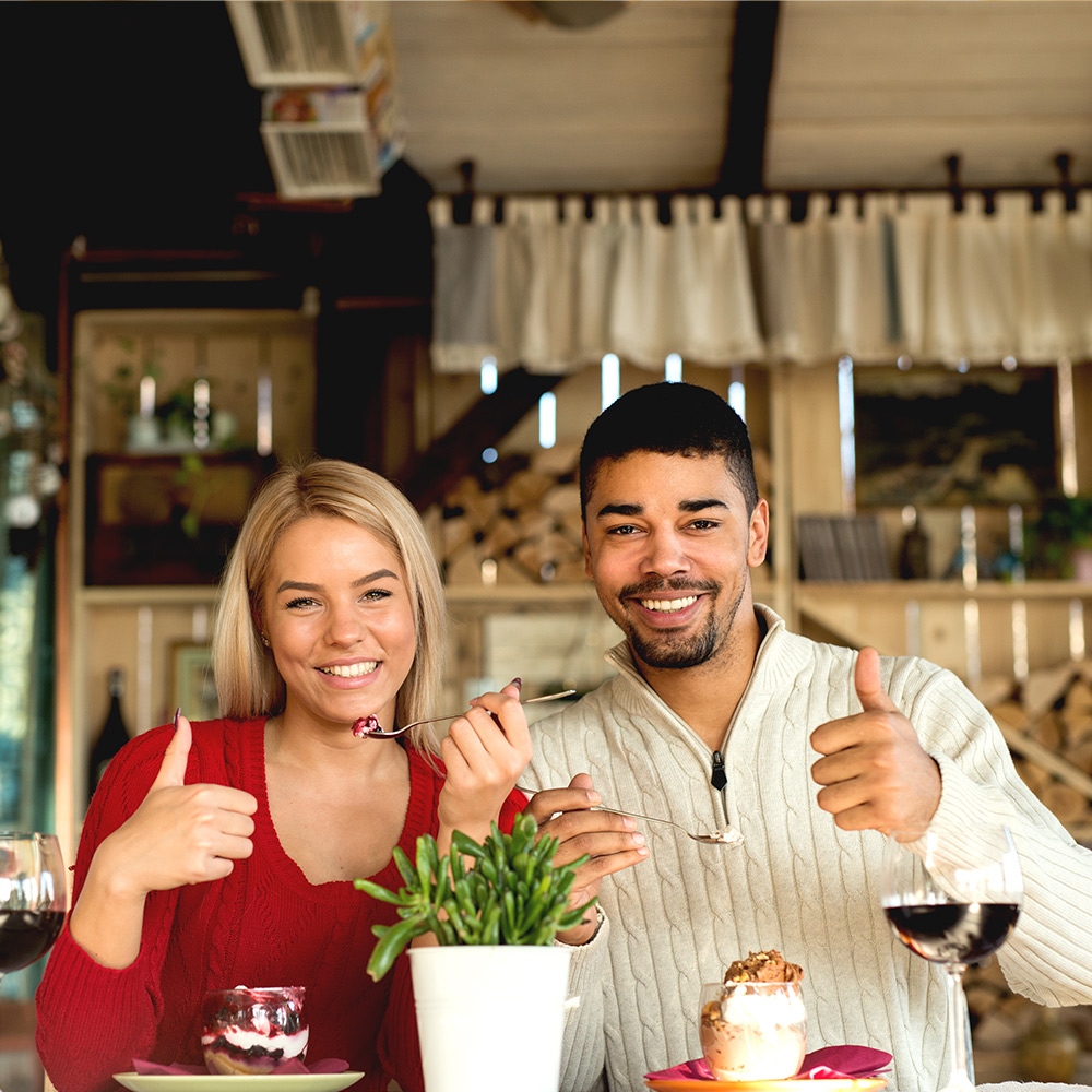 Man and woman giving "thumbs up" in restaurant 
