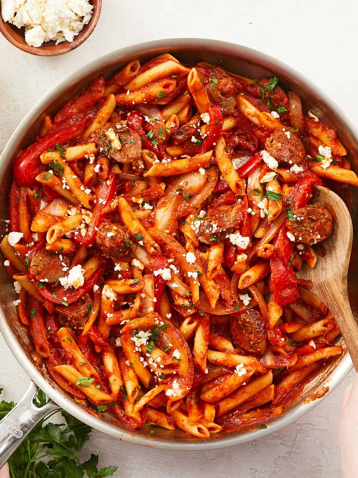 Close up of a skillet full of pasta with sausage and peppers.