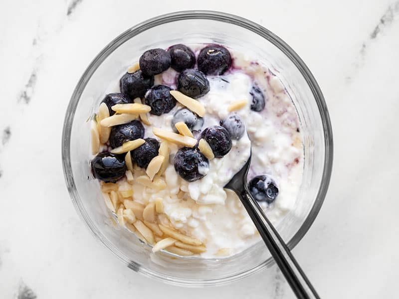 Cottage cheese, blueberries, sliced almonds, and honey in a glass meal prep container