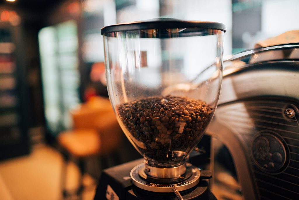 Whole coffee beans beside a coffee grinder