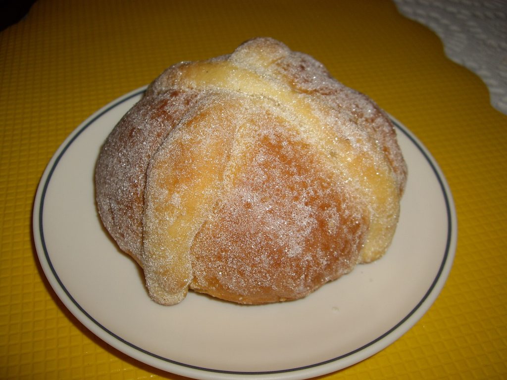 A round pan de muerto loaf decorated with dough bones and sugar