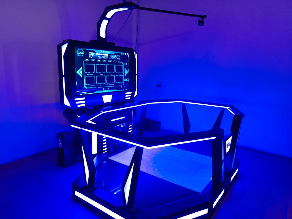 A sleek VR gaming setup with bright blue LED lights, a large central screen, a hexagonal frame for movement, a