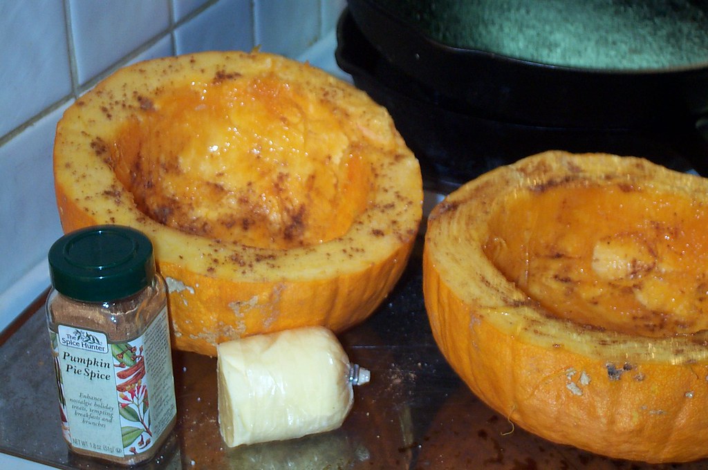 Halved pumpkin roasted cut side down on a baking tray