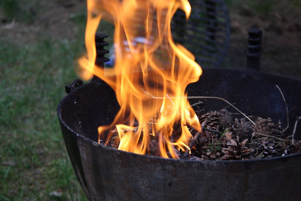 A wood-fired barbecue smoker pit with smoke rising
