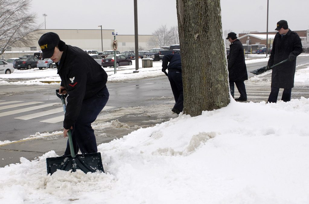 A snow shovel leaning against a cleared sidewalk