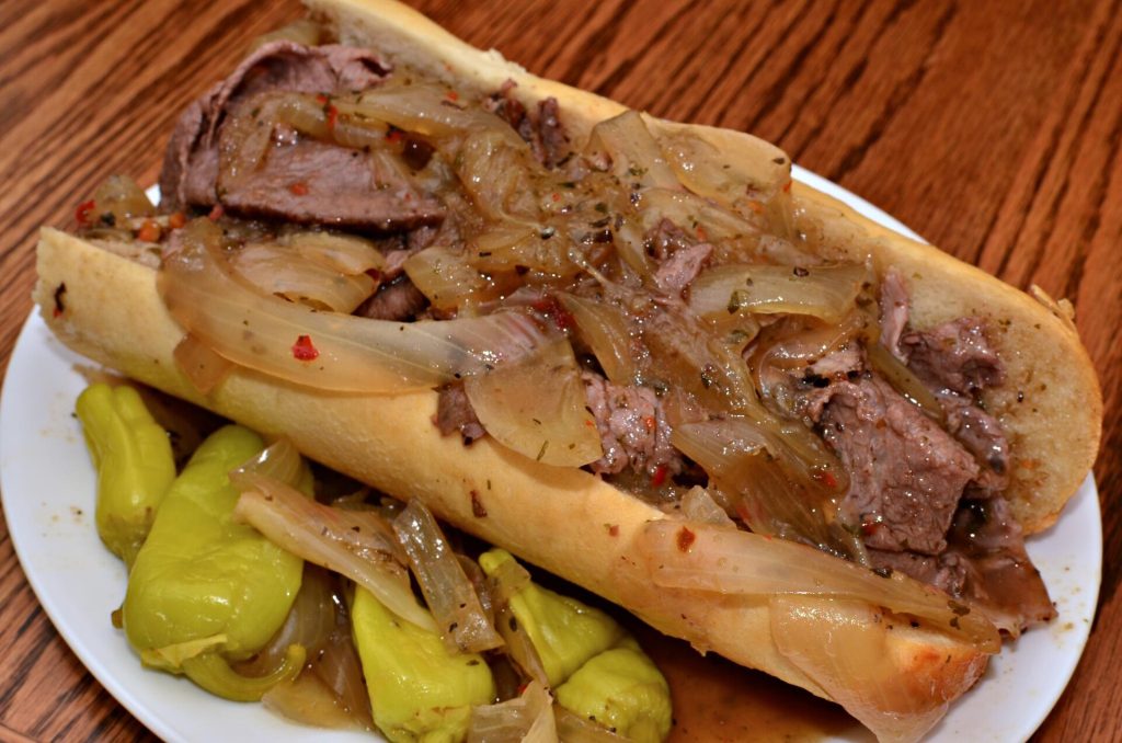 An Italian beef sandwich soaked in jus and topped with giardiniera
